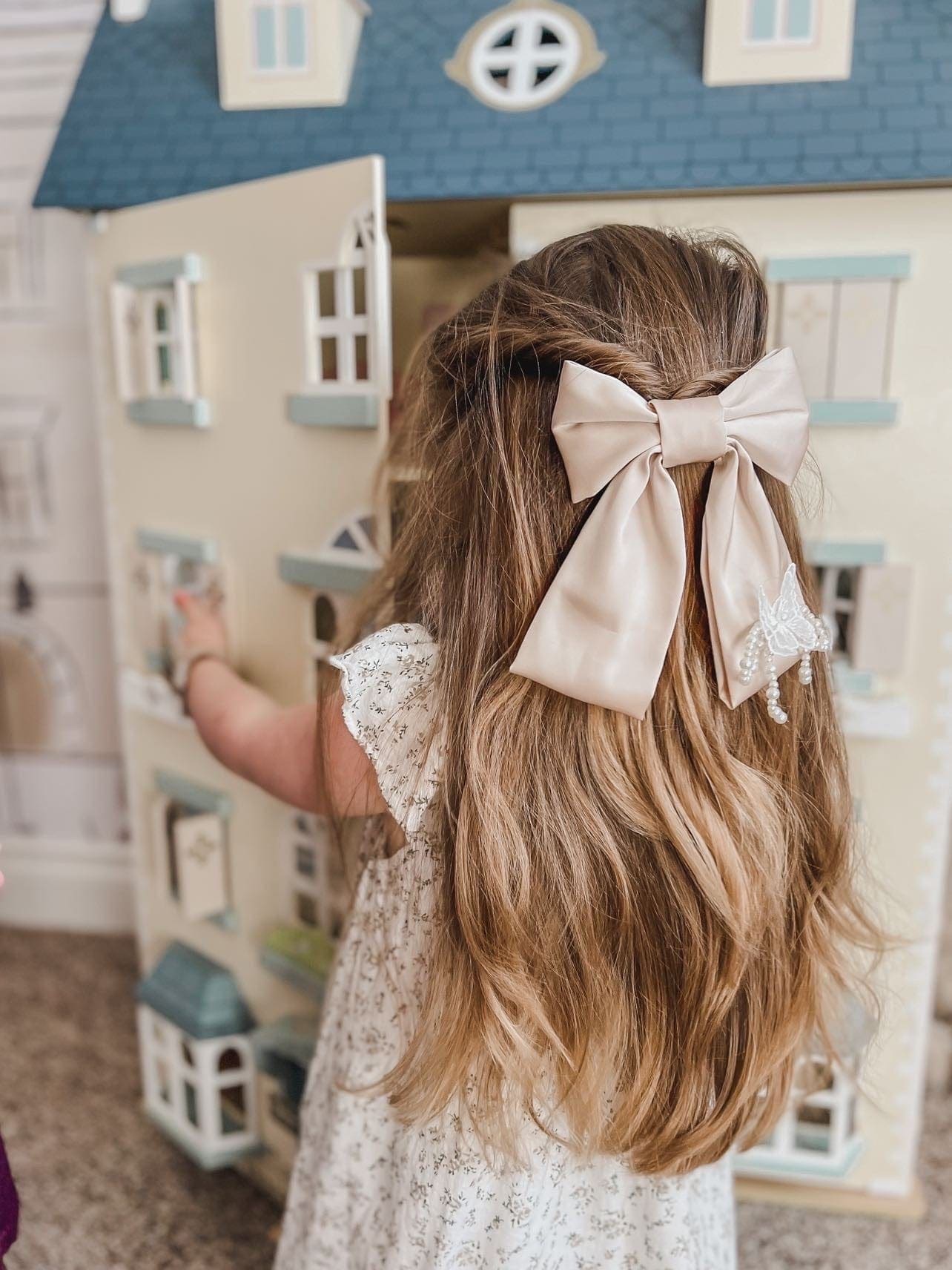Young girl wearing Anise Satin Embroidered Hair Bow in champagne with butterfly detail