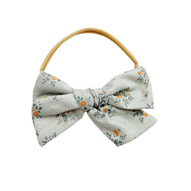 Light grey wildflower print baby headband with front bow, soft elastic wrap, and secure comfortable fit for newborns and toddlers.