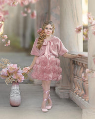 girl in a pink fluffy bolero jacket faux fur with floral skirt standing in a decorative setting with flowers and columns.